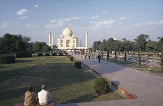 INDIA, Uttar Pradesh, Agra, Taj Mahal and gardens with couple sitting in the foreground and other