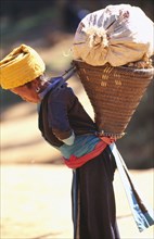 THAILAND, North, Hilltribe village woman carrying loaded basket on her back