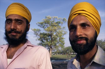 INDIA, Delhi , "Two Sikh men, head and shoulders portrait wearing orange turbans."