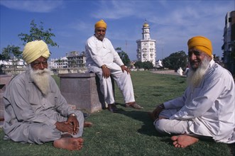 INDIA, Punjab, Amritsar, Golden Temple.  Three elderly Sikh men sitting outside the temple complex.