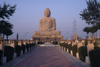 INDIA, Bihar, Bodh Gaya, Giant seated Buddha statue seen from pathway leading up to the base.