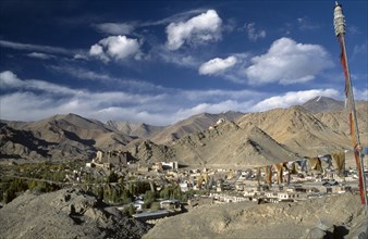 INDIA, Ladakh, Leh Valley , Prayer flags hanging above village set in mountainous landscape with