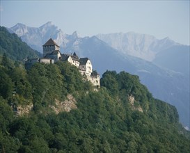 LIECHTENSTEIN, Vaduz, "The Castle nestling in  wooded hillside, rugged mountains behind "