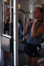 10044897 SPORT Fitness Gym Man working on biceps on weight machine.