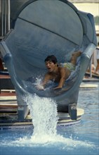 10044921 CHILDREN Leisure Swimming Boy sliding head first down water slide in pool