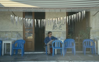 GREECE, Peloponnese Islands, Gythion, Squid hanging up to dry outside cafe/taverna.