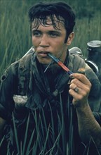 VIETNAM, War, 1968, 9th Division soldier near Tan An sitting in a rice paddy smoking Cambodian Red