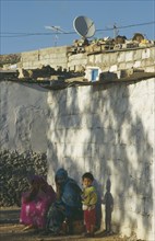 MOROCCO, General, Women and child outside slum housing with satellite dish on the roof