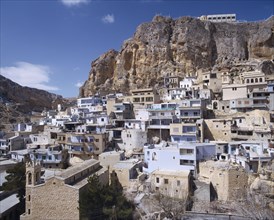 SYRIA, South,   Maalula, "Blue & white square houses built under & into rock face, churches "