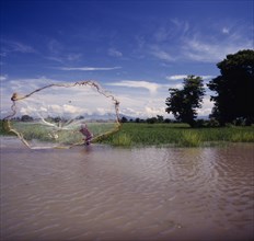 INDONESIA, Lombok, Praya, Boy casting fishing net into lake