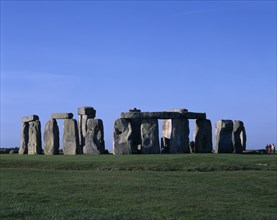 ENGLAND, Wiltshire, Stonehenge, View across the grass on Salisbury Plain toward standing stones