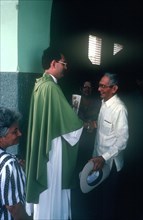 CUBA, Guimero, Priest shaking the hand of one of his worshipers exiting the church
