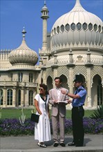 ENGLAND, East Sussex, Brighton, Policeman giving tourist couple directions outside the Royal