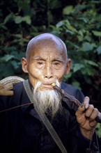 CHINA, South, Portrait of an old man smoking a pipe