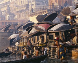INDIA, Uttar Pradesh, Varanasi, Umbrellas over the ghats along the River Ganges.