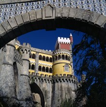 PORTUGAL, Estremadura, Sintra, Pena Palace. View through archway to yellow and red tower with