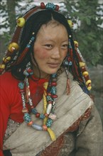 CHINA, Qinghai, Golmud, Tibetan woman in traditional clothes wearing beads in hair and around neck