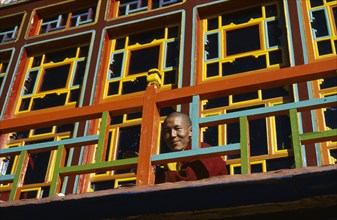 TIBET, Gyantse, Palkhor Choide , Monk looking over brightly painted colourful Monastery  balcony