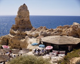 PORTUGAL, Algarve, Algar Seco, Beach cafe in rocks beside a tall weathered rock