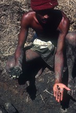 SRI LANKA, Ratnapura, Gem miner displaying gems in one hand and unpanned mud in other.