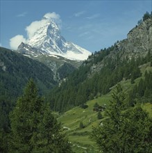 SWITZERLAND, Valais, Zermatt, The snow capped Matterhorn towering above a green valley