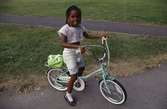 10037908 ENGLAND  London Young black girl on bicycle on Clapham Common.