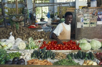 TANZANIA, Zanzibar Island, Smiling vendor behind fruit and vegetable stall in Zanzibar town.