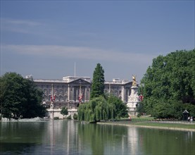 ENGLAND, London, Buckingham Palace. View from Green Park with trees surrounding lake and fountains