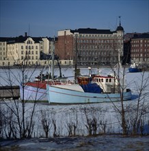 FINLAND, Uusimaa, Helsinki, "North Harbour,fishing boats,frozen sea,buildings beyond "