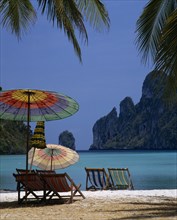 THAILAND, Krabi, Phi Phi Island, Beach in enclosed bay with deckchairs and umbrellas beneath