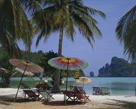 THAILAND, Krabi, Phi Phi Island, Beach in enclosed bay with deckchairs and umbrellas beneath
