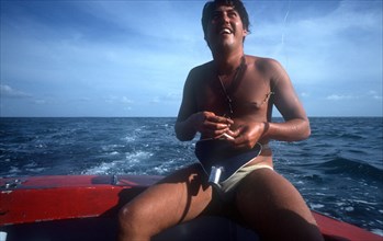 CUBA, Ciego de Avila, Cayo Guillermo, Man sitting at the back of a boat putting bait on the end of