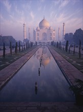 INDIA, Uttar Pradesh, Agra, The Taj Mahal in pink misty light with the pool in the foreground