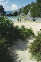 BERMUDA, Jobsons Cove, Couple at water’s edge looking out to sea in secluded bay