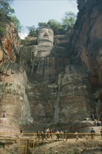 CHINA, Sichuan, Leshan, Dafu or Grand Buddha carved into cliff face with visitors behind railings