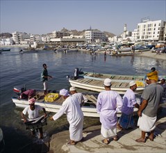 OMAN, Capital Area, Matrah, Fish Souk with locals unloading a catch at jetty. Boats and the