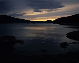 CANADA,  Quebec, Tadoussac, "Saguenay River at dusk,car ferry,grey/gold sky,silhouetted hills "