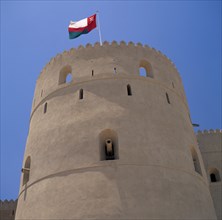 OMAN, Western Hajar, Rustaq  , Fort.  Round tower with cannons in walls and Omani flag flying