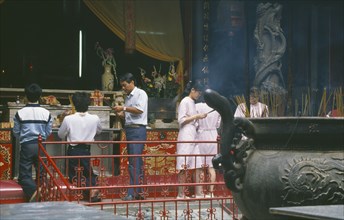 TAIWAN, Tainan, People making offerings of incense at temple.