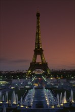FRANCE, Ile De France, Paris, Eiffel Tower illuminated at dusk with illuminated fountains in the