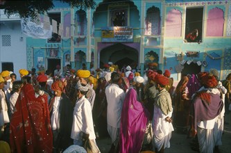 INDIA, Rajasthan, Pushkar, A crowded street of people walking in front of brightly coloured