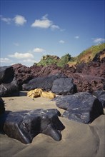 INDIA, Goa, Keri Beach, "Coastal landscape.  Large black, yellow and red rocks in the sand"
