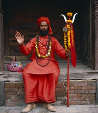 NEPAL, Kathmandu, Full length portrait of holy Man dressed in red.