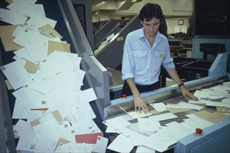 ENGLAND, East Sussex, Brighton, Mail sorting office.  Male worker sorting through letters on