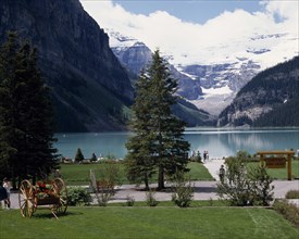CANADA, Alberta, Lake Louise, Chateau Lake Louise gardens with the lake and snow capped peaks in