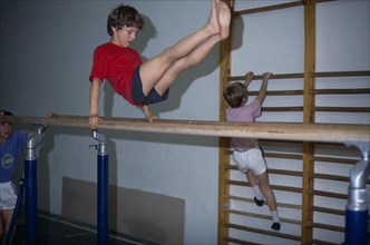10018121 SPORT Gymnastics Children Boys using parallel bars and climbing frame in Holland.