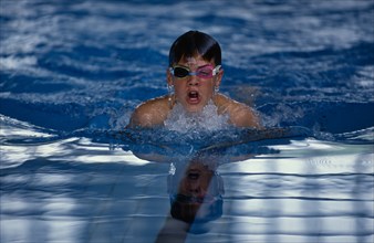 SPORT, Watersport, Swimming, Boy wearing swimming goggles doing breaststroke in indoor pool.