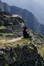 PERU, Cusco, Machu Picchu , Piper sitting at the ruined city playing the flute   Cuzco