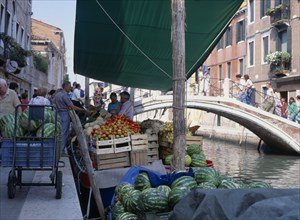 ITALY, Veneto, Venice, Fruit and vegetable stall on a boat on the riverbank near a small bridge