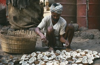INDIA, Goa, Colva, Man laying out cut coconuts to dry in the sun for copra oil